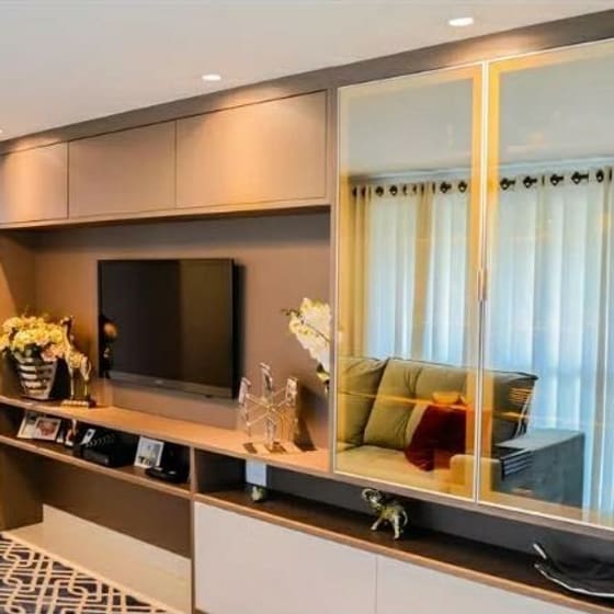 Painel de TV planejado com nichos, armários aéreos e portas de vidro com iluminação